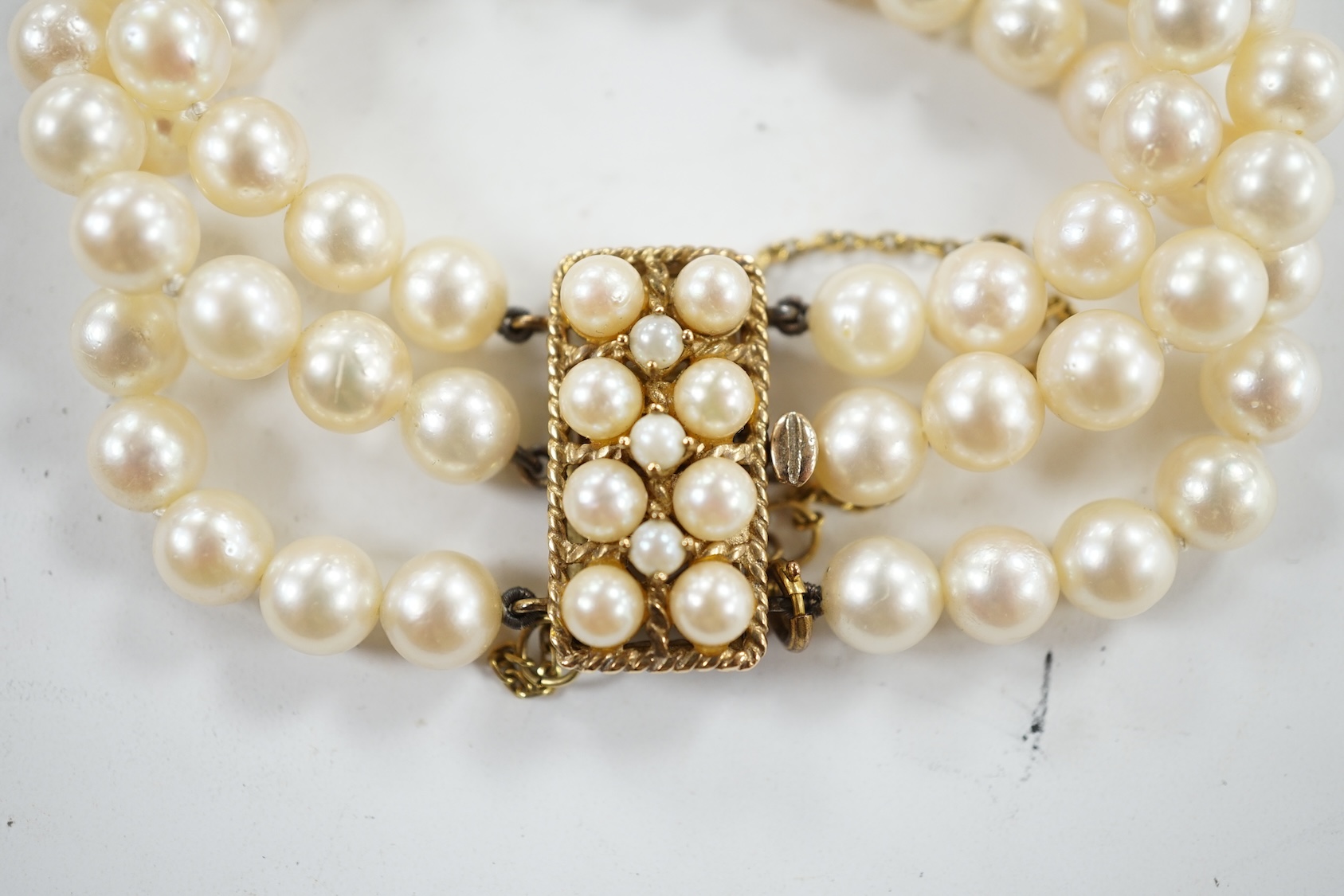 A triple strand cultured pearl necklace, with 9ct and cultured pearl clasp and spacer, 18cm. Condition - fair